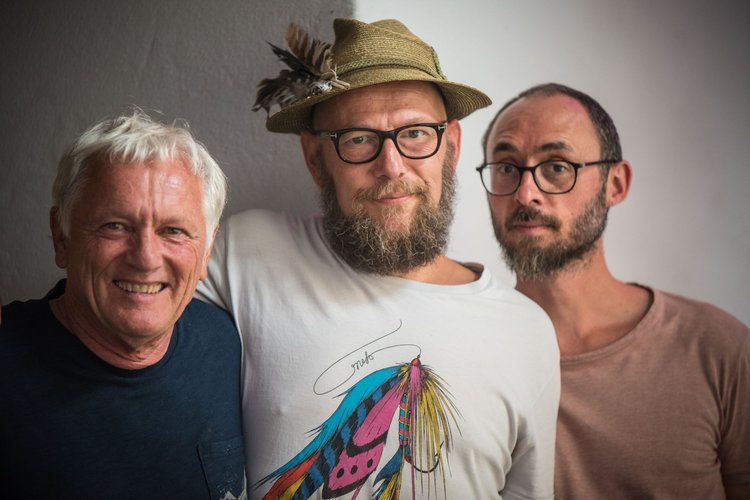 Drei Männer blicken in die Kamera.