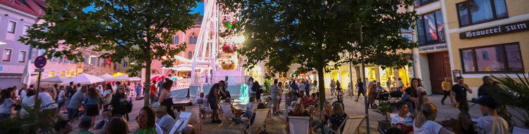 Menschen abends auf Liegestühlen vor Riesenrad und Pfaffenhofener Rathaus