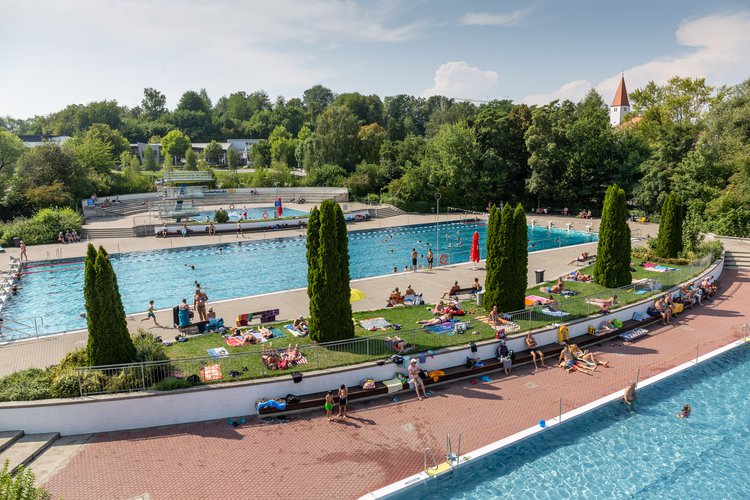 Ansicht auf Schwimmerbecken und Springerbecken von oben mit einigen Badegästen am und im Wasser