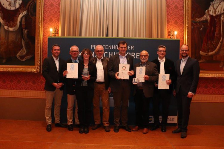 Gruppenfoto der Gewinner des Klimaschutzpreises 2019. 6 Gewinner und Herr Herker und Herr Andreas Herschmann stehen auf der Bühne im Festsaal des Rathauses. Die Gewinner halten die Preise und die Urkunden in die Höhe.
