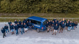 Circa 30-köpfige Team des Rufbusses steht vor einem Rufbus vauf einem Parkplatz