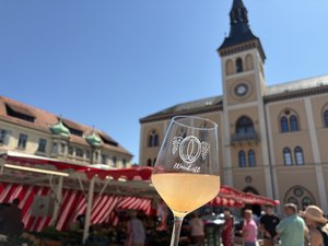 Weinglas, das vor dem Rathaus in die Luft gehalten wird mit der Aufschrift Weinkistl