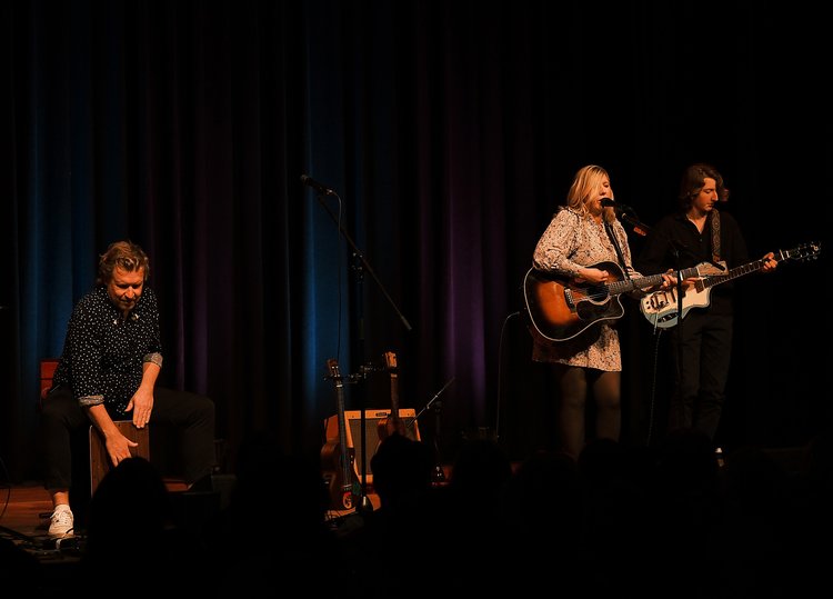 Claudia Koreck mit Gitarre und ihrem Ehepartner auf der Bühne; und ein Gitarrist