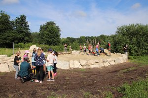 Das Sandarium - eine Sandfläche mit Pflanzen und abgestorbenen Ästen. Kinder schütten dort Sand auf und pflanzen an.