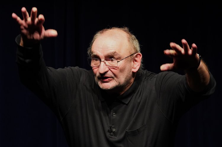 Sigi Zimmerschied vor schwarzem Hintergrund hält die Hände nach oben