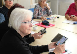 Ehrenamtlichen Trainer helfen, Senioren den Umgang mit dem Smartphone zu erleichtern.

