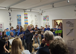 Foto 1: Reinhard Haiplik eröffnete die Vernissage; im Hintergrund die Bläserklasse der Georg-Hipp-Realschule. 