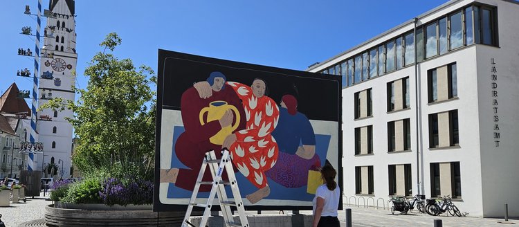 Livemalaktion einer Künstlerin auf dem Hautplatz bei blauem Himmel