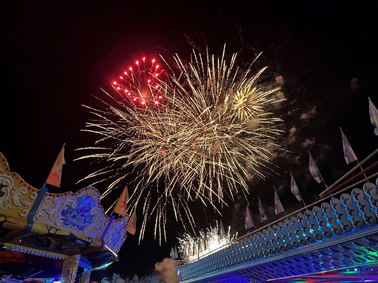 Volksfest in der Nacht, am Himmel Feuerwerk und ein Herz