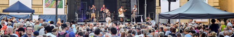 Publikum vor der Bühne vor dem Haus der Begegnung und eine Band spielt Musik.