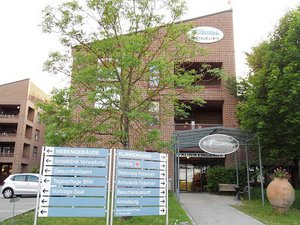 Wegweiser und Gebäudeansicht der Klinik