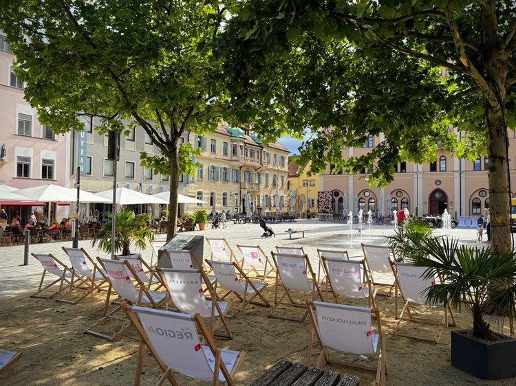 Foto mit Liegestühlen auf Sand vor dem Rathaus